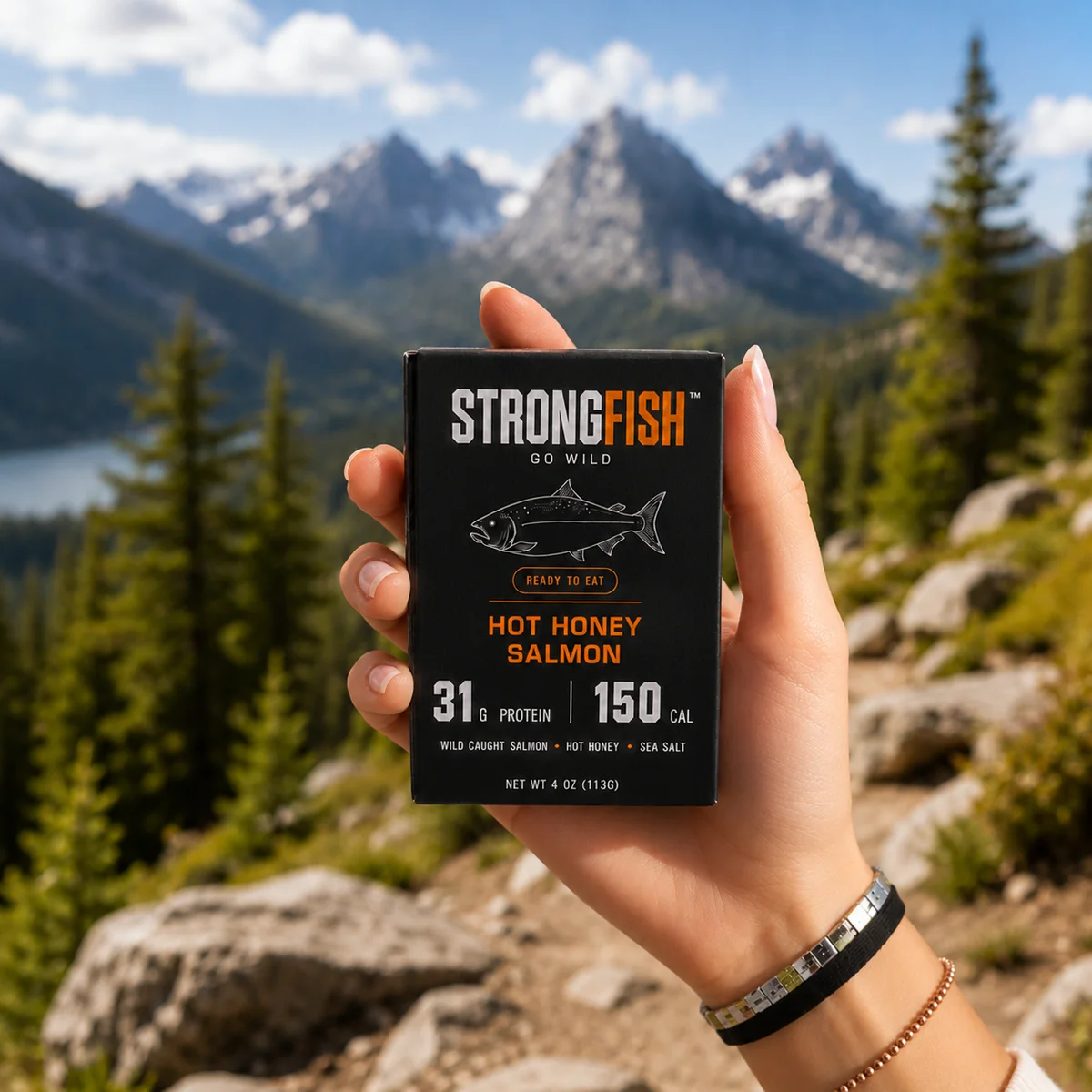 STRONGFISH Hot Honey Salmon carton held up against mountains